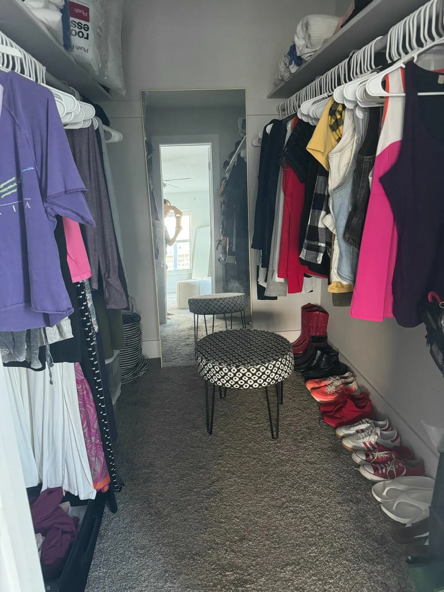 Wall-mounted shelving with built-in hanging rods, full-length mirror, and neutral-toned carpeting