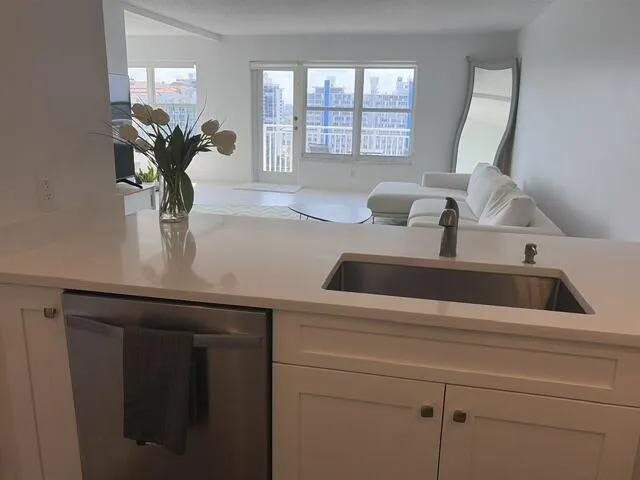 Kitchen island with a stainless steel undermount sink, brushed nickel faucet, and integrated stainless steel dishwasher