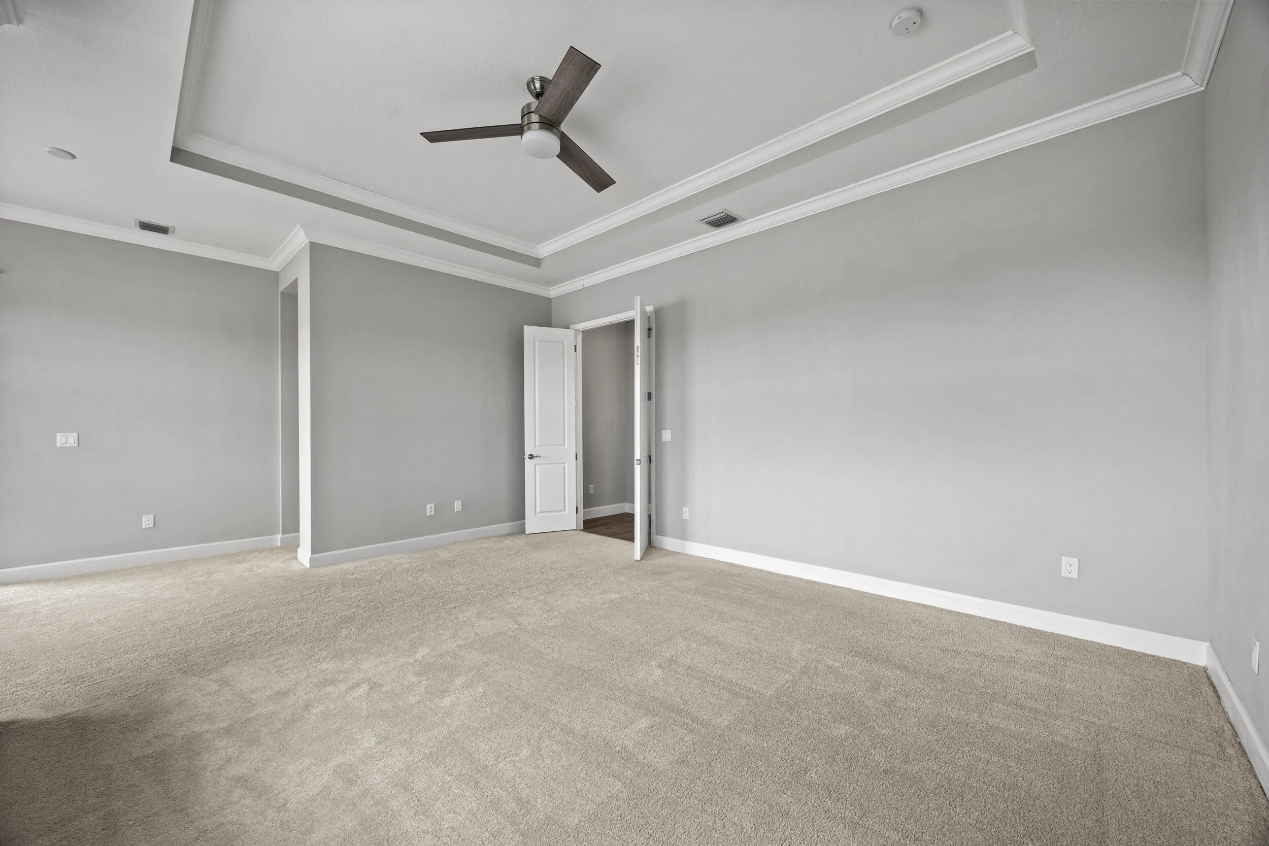 Tray ceiling with crown molding, ceiling fan, and light gray wall paint