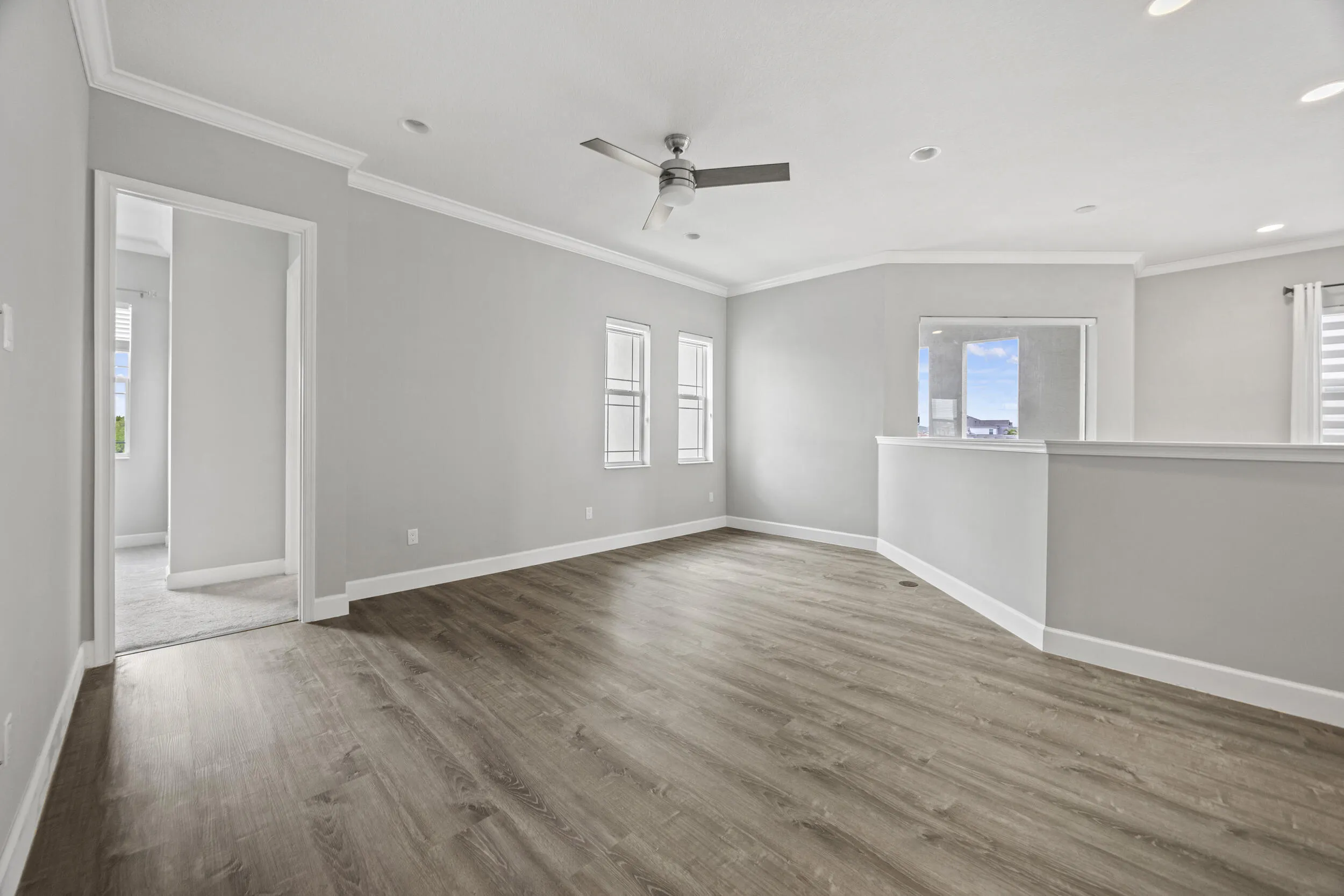 Spacious room featuring wood-finish flooring, recessed lighting, and a ceiling fan