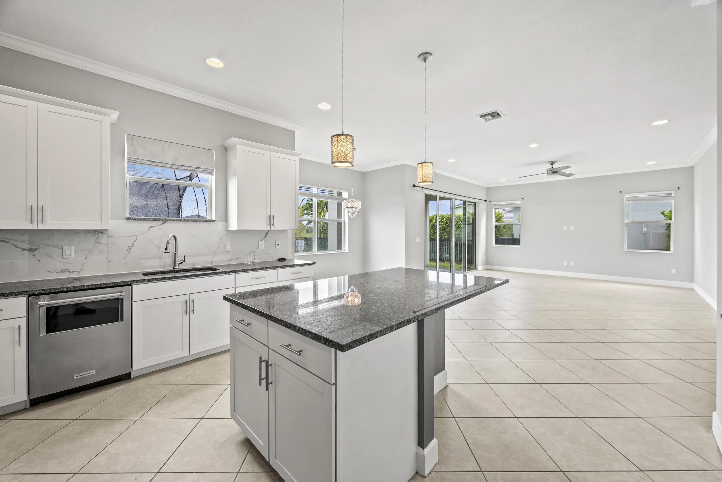 Spacious kitchen featuring white cabinetry, granite countertops, and a full-height backsplash