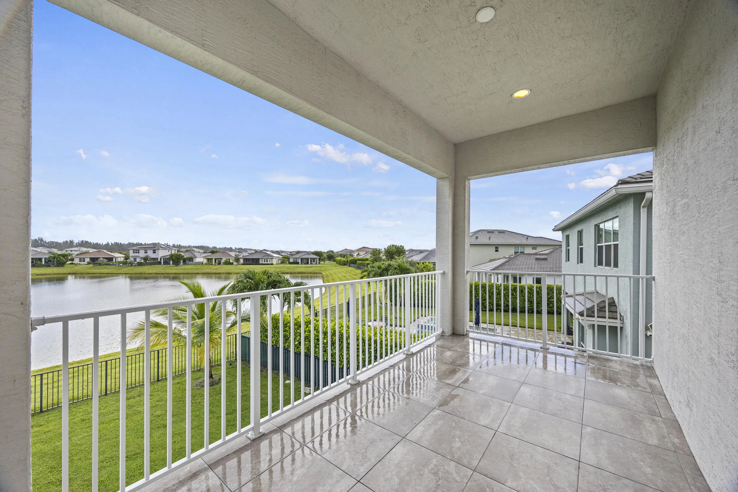 Covered balcony featuring tile flooring and white railings