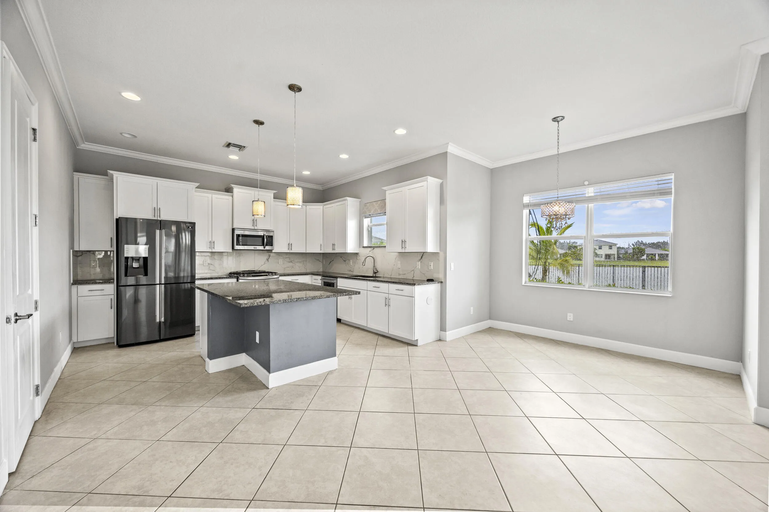 Expansive kitchen with white cabinetry, a center island with a stone countertop, a stainless steel appliance suite, and tile flooring