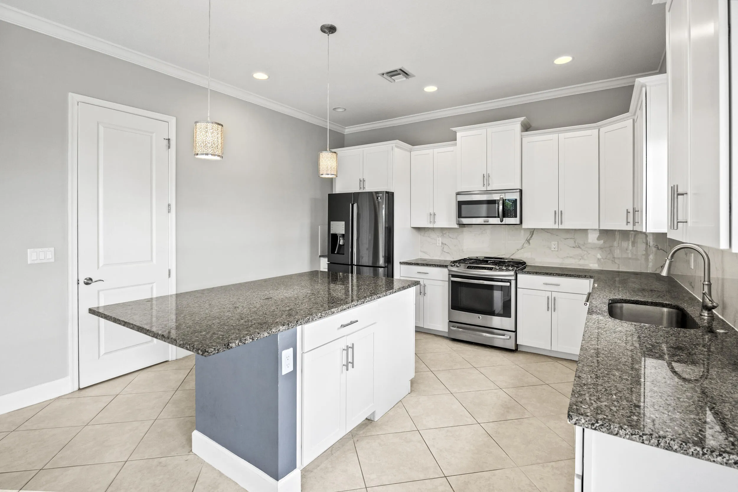 Kitchen featuring a central island with countertop, stainless steel appliances, white cabinetry, and tile flooring