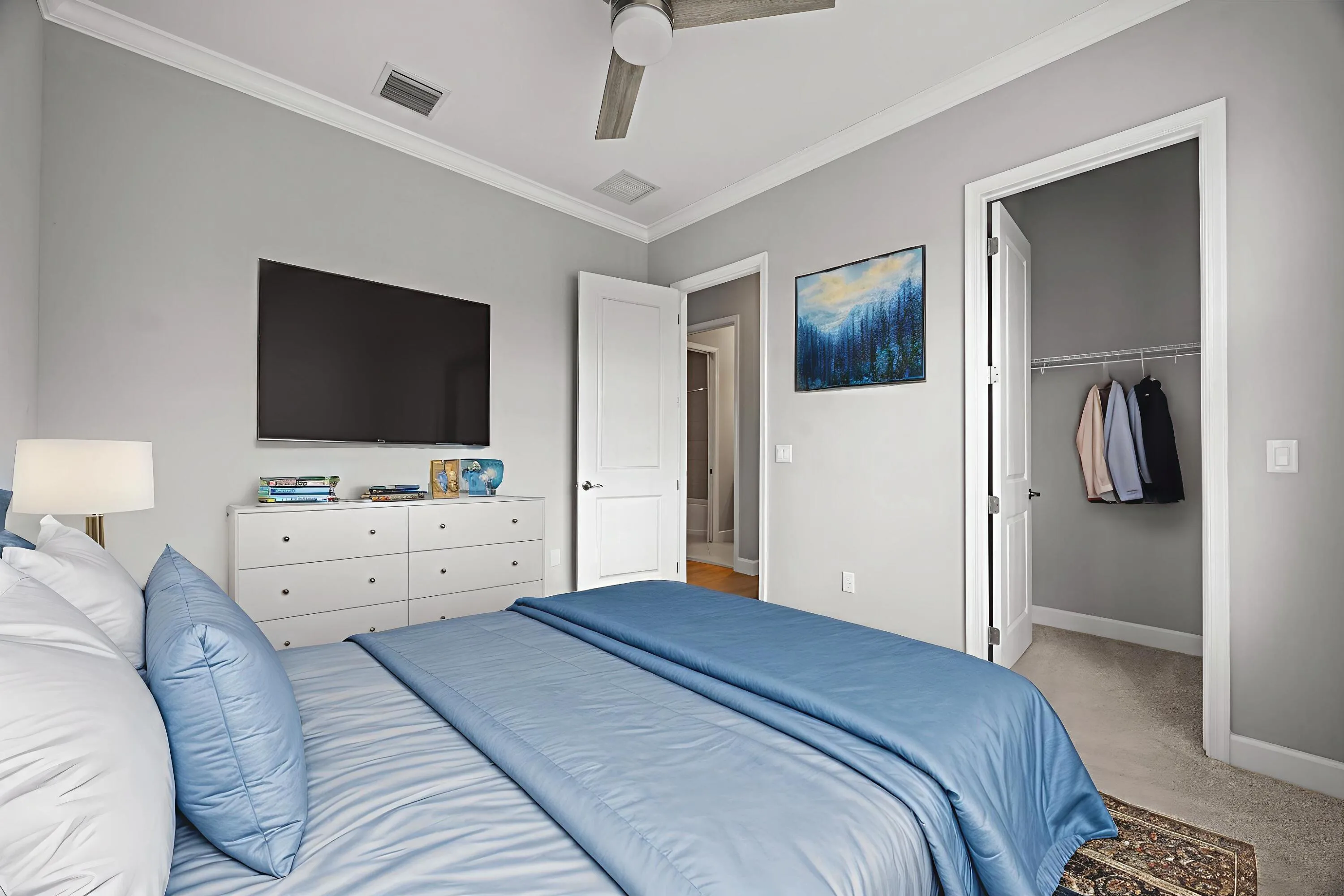 Neutral-toned room featuring crown molding, a ceiling fan, and a built-in closet with wire shelving