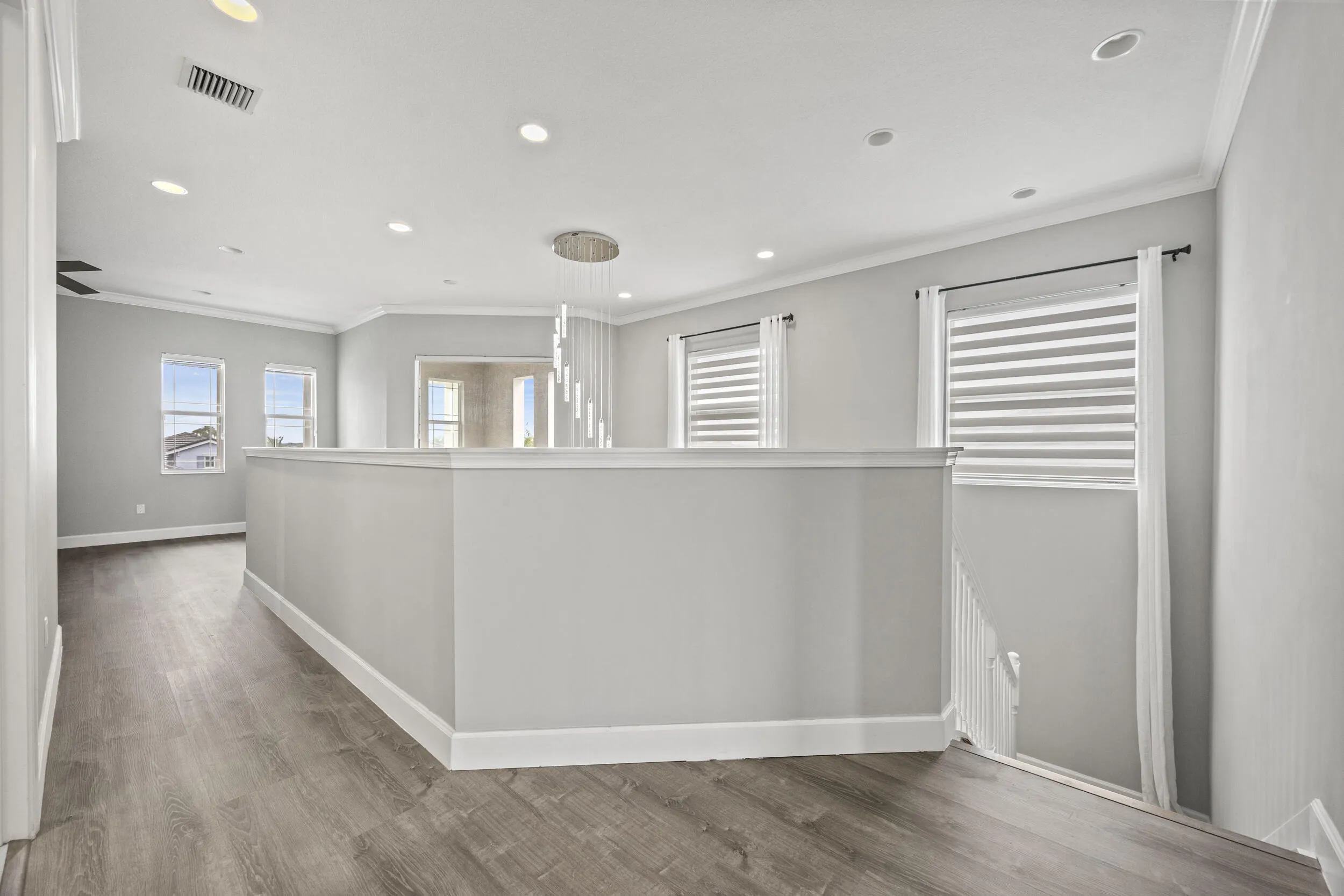 Wood-finish flooring, recessed lighting, crown molding, and multiple windows with blinds