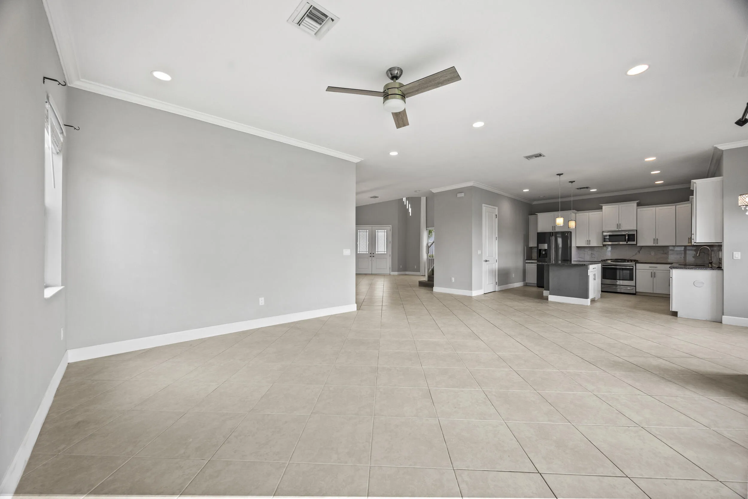 Expansive open-concept living area featuring tile flooring, recessed lighting, and a ceiling fan