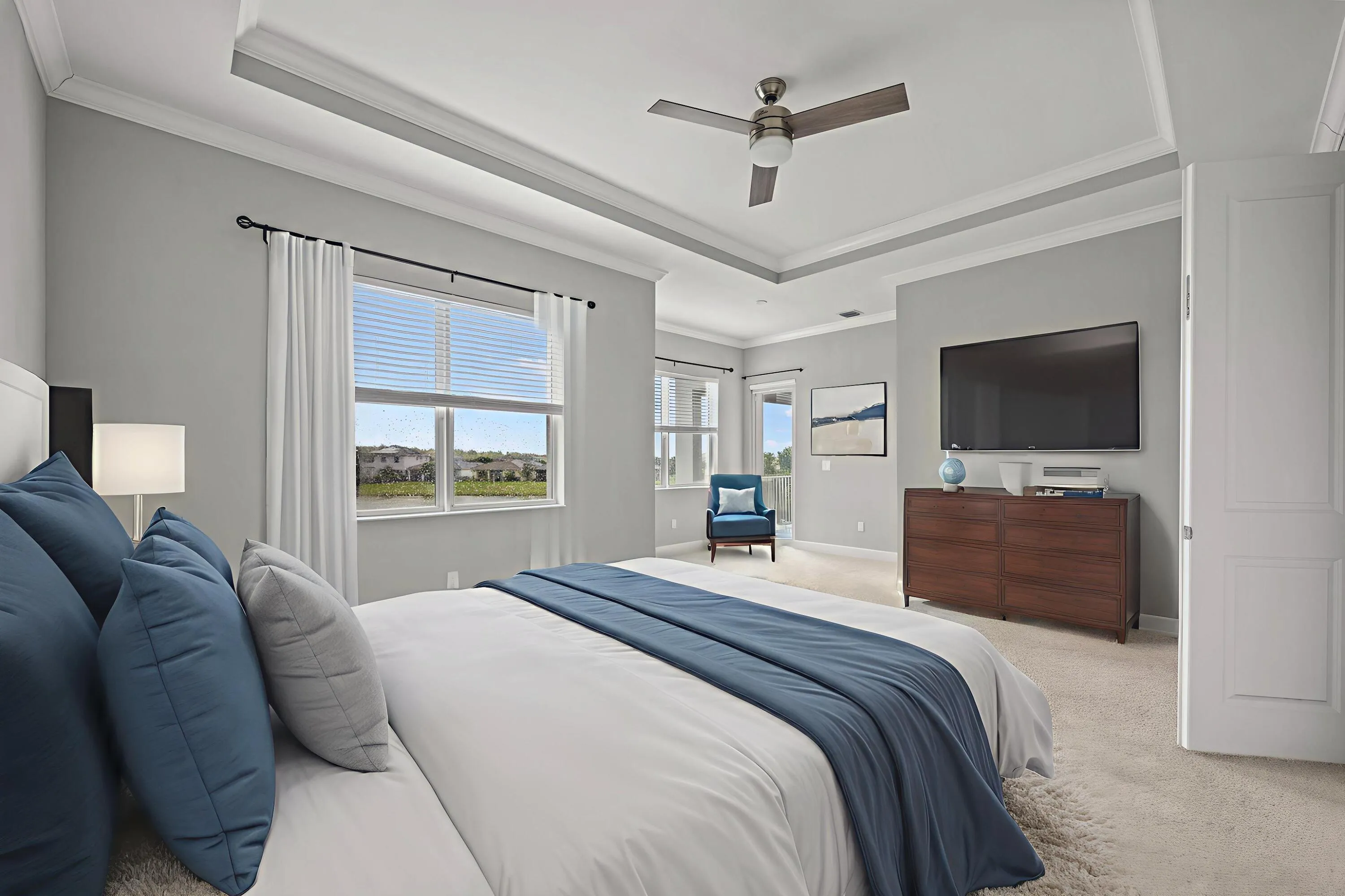 Tray ceiling with crown molding, ceiling fan, and large windows with blinds