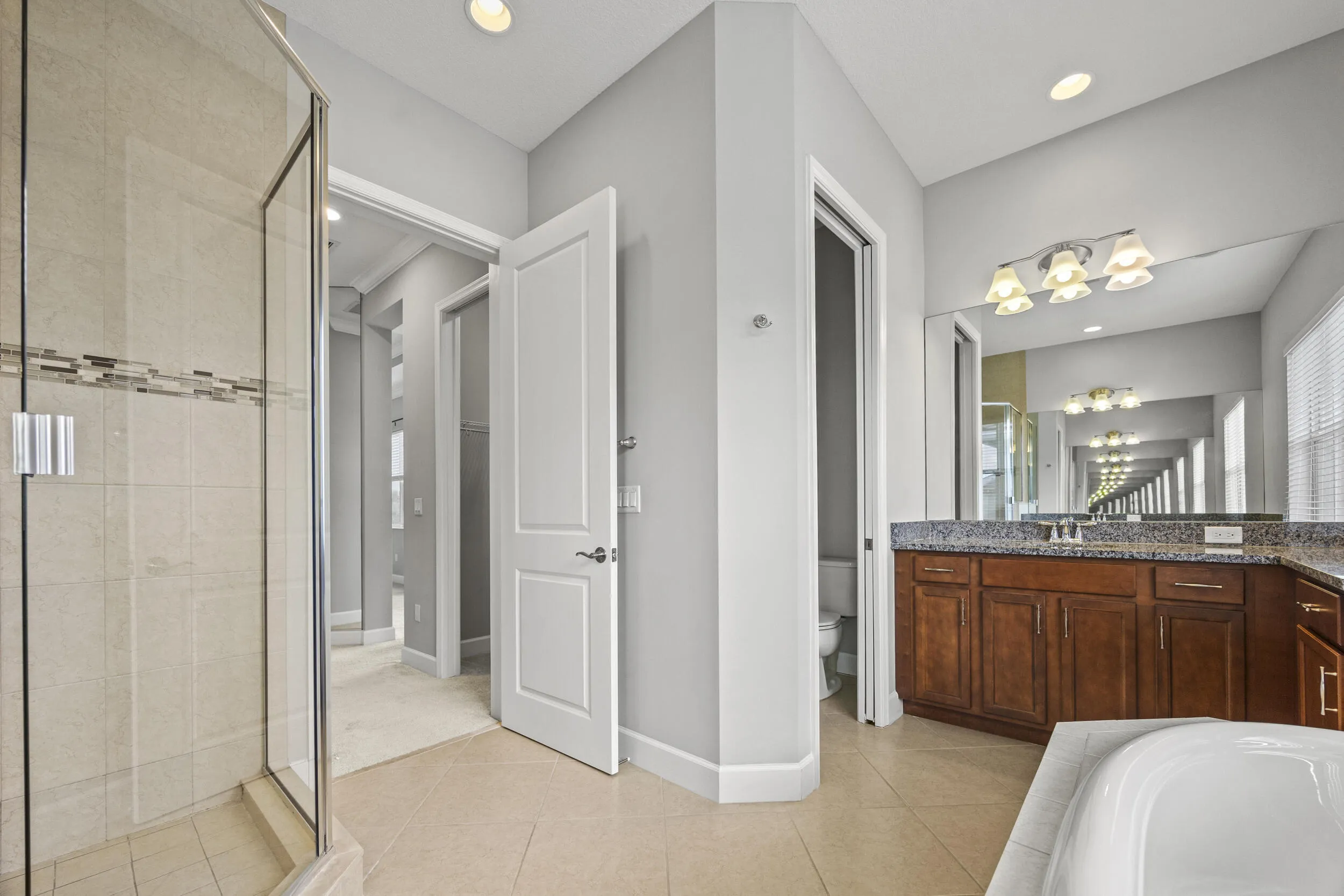 Glass-enclosed shower with tiled walls and decorative accent band
