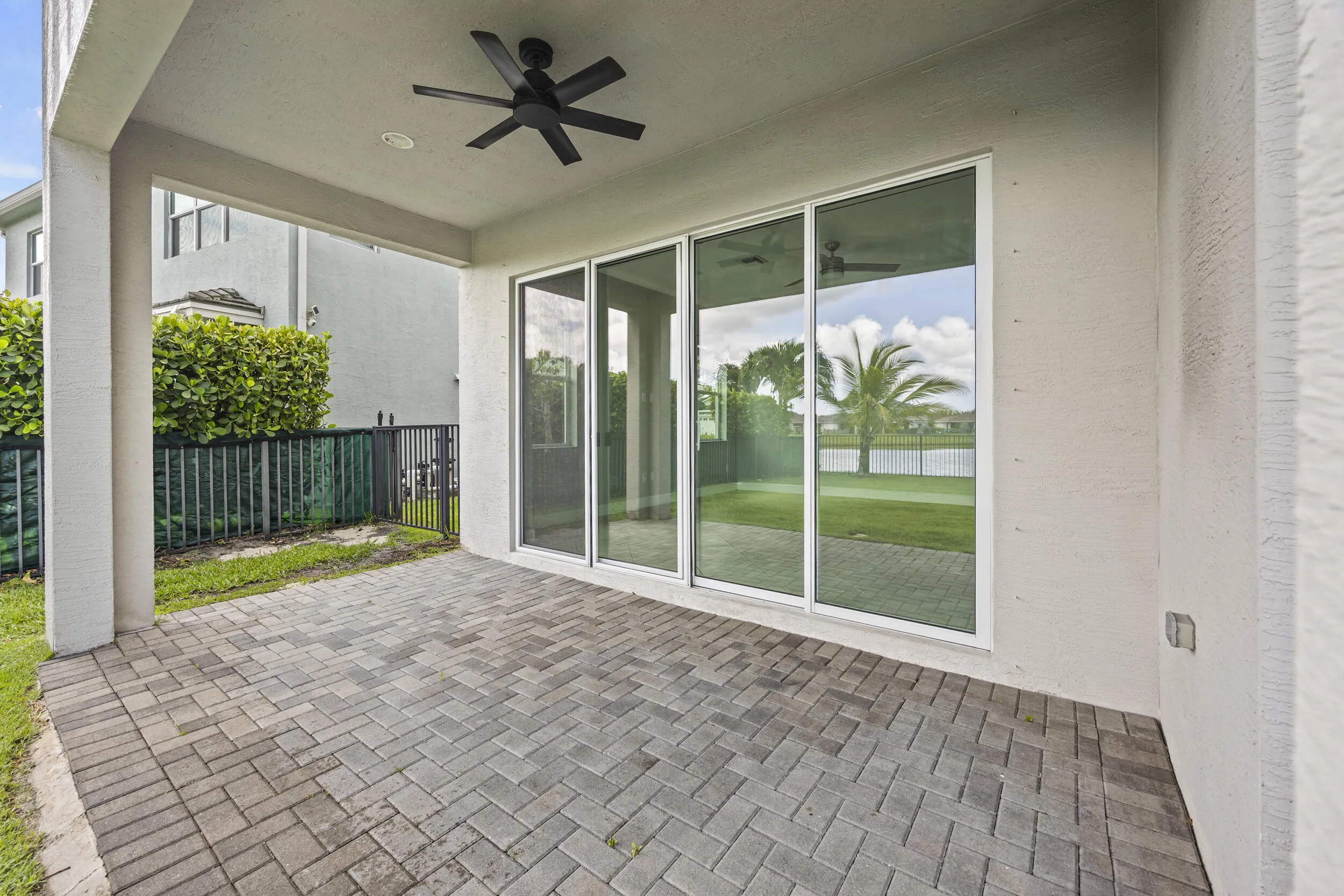Covered patio with paver flooring, overhead fan, and large sliding glass doors