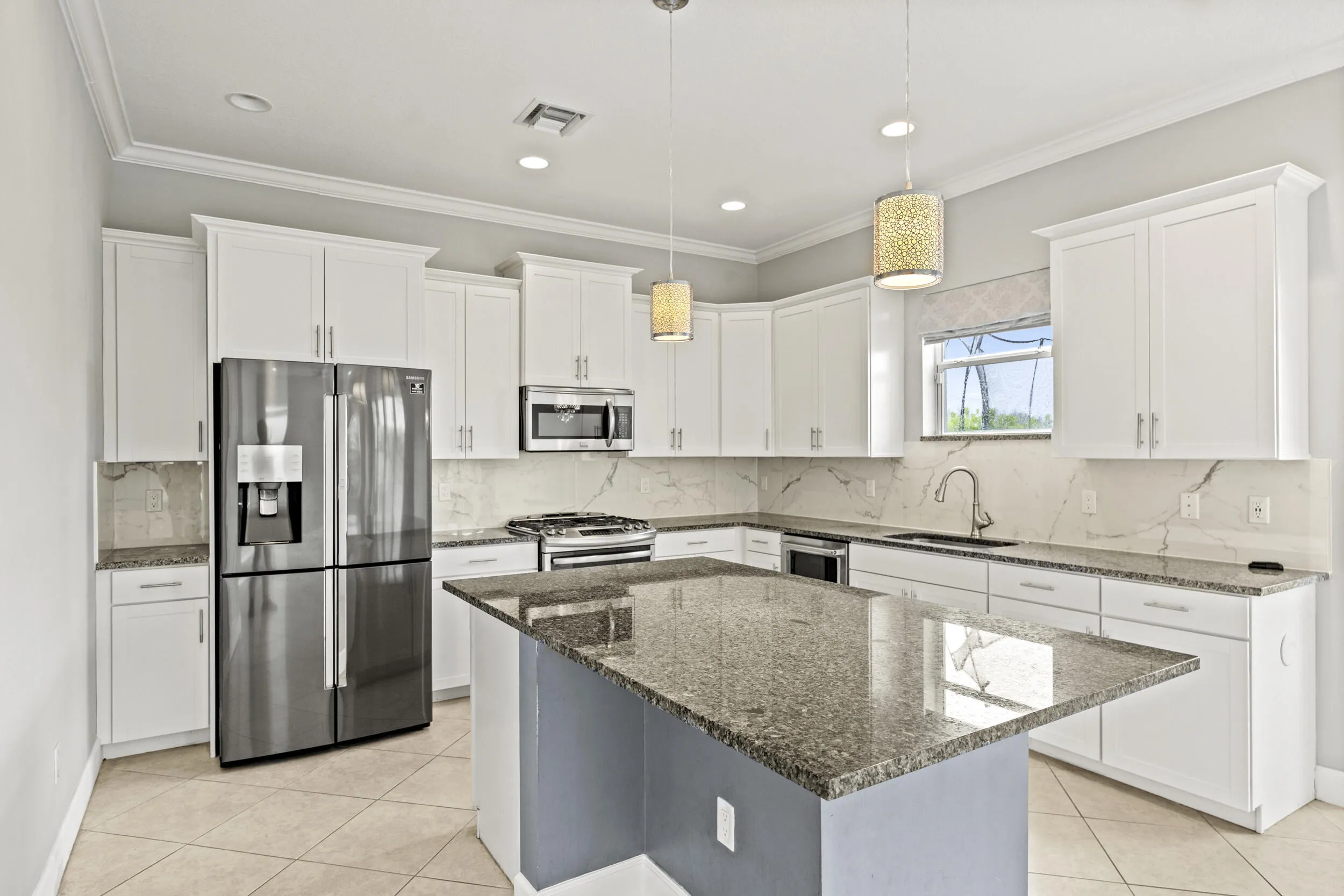 Kitchen featuring white cabinetry, stainless steel appliances, granite countertops, and a central island