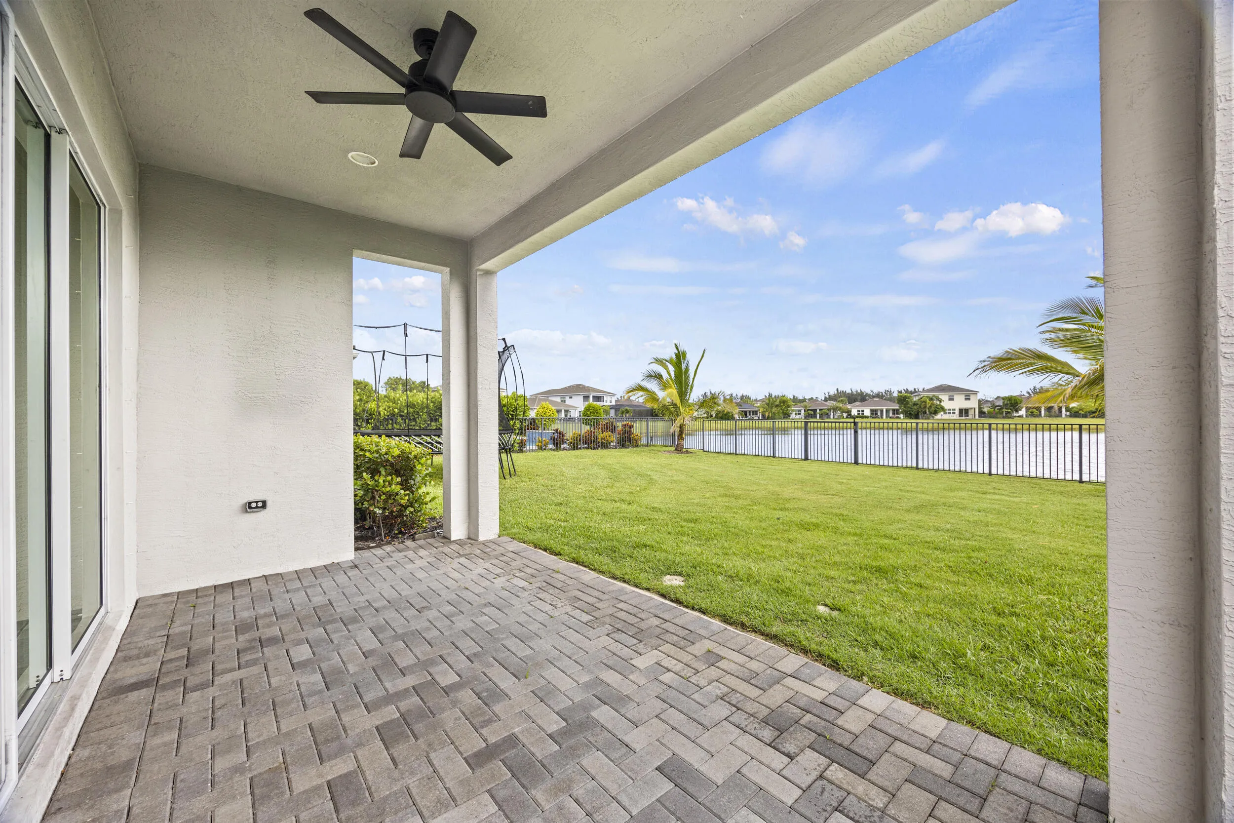 Covered patio with paver flooring, overhead ceiling fan, and sliding glass doors
