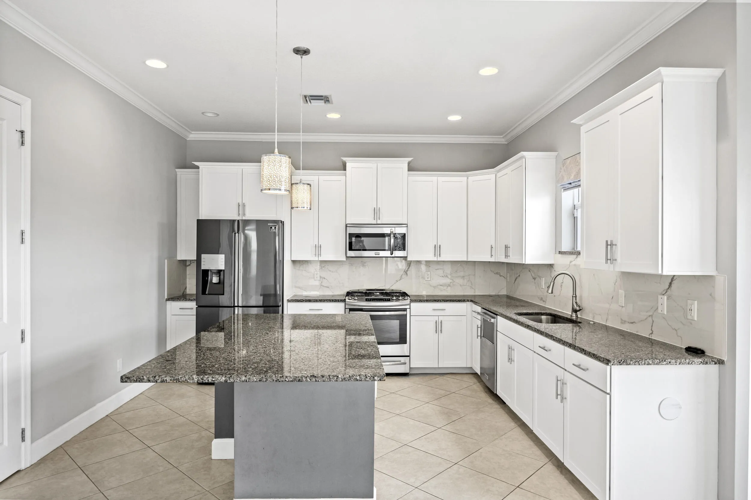 Kitchen featuring white cabinetry, granite countertops, tile flooring, stainless steel appliances, and pendant lighting