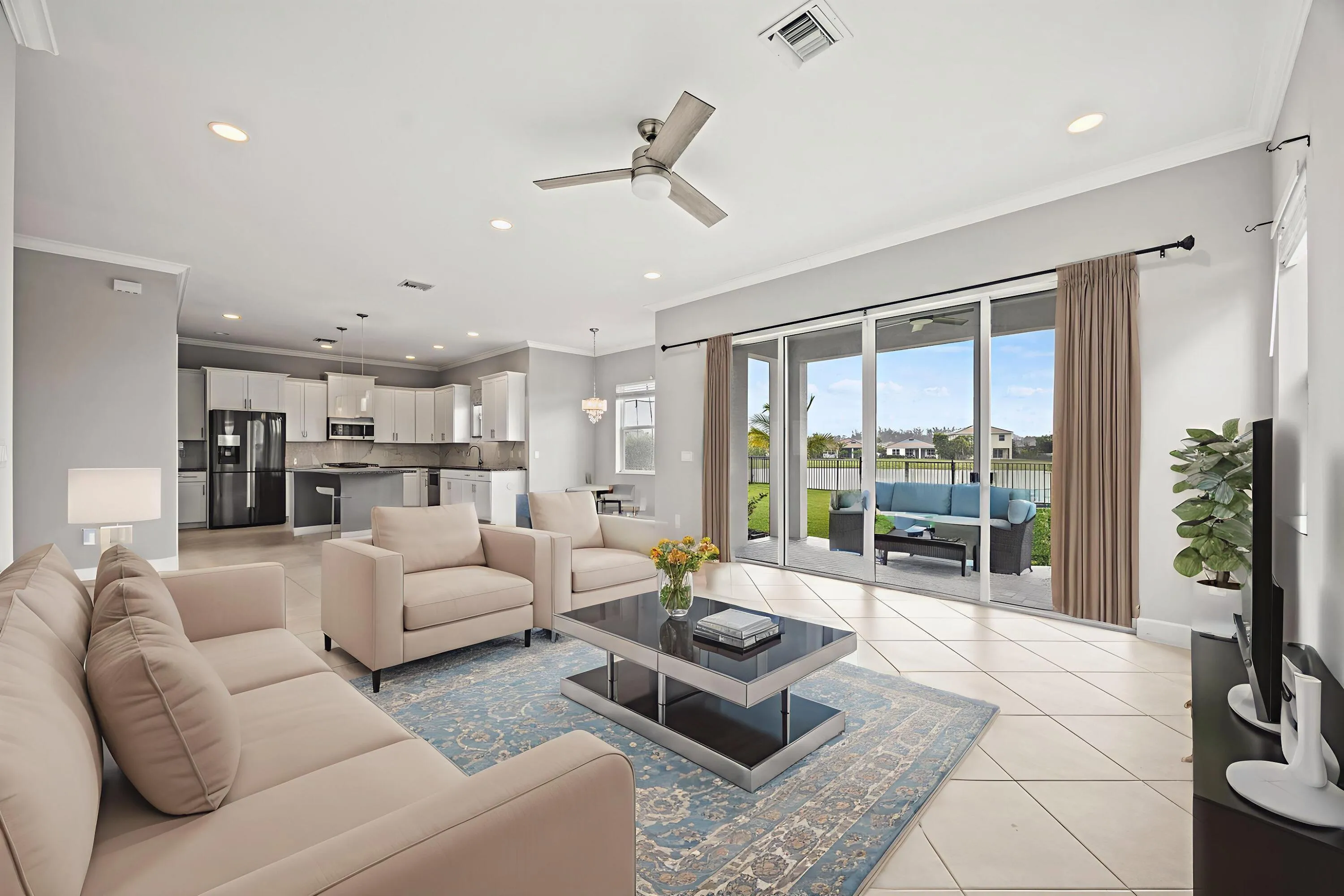 Spacious open-concept living area featuring large format tile flooring, crown molding, and recessed lighting
