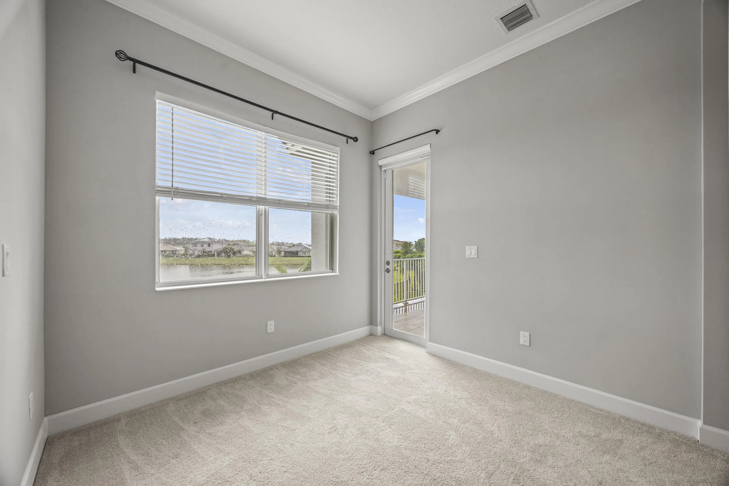 Wall-to-wall carpeting, crown molding, and a sliding glass door to a private balcony