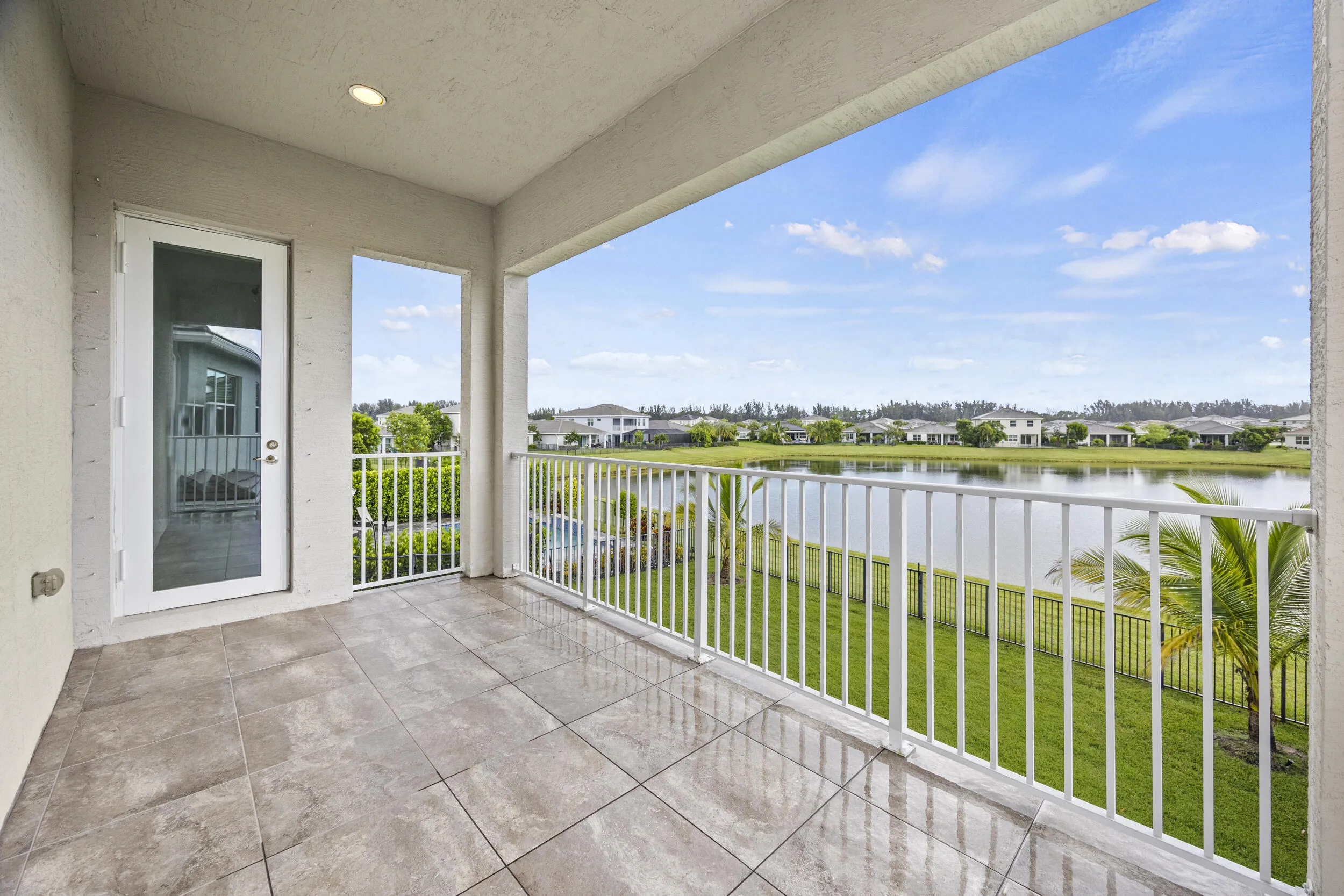 Spacious balcony with tiled flooring, white metal railing, and expansive water frontage
