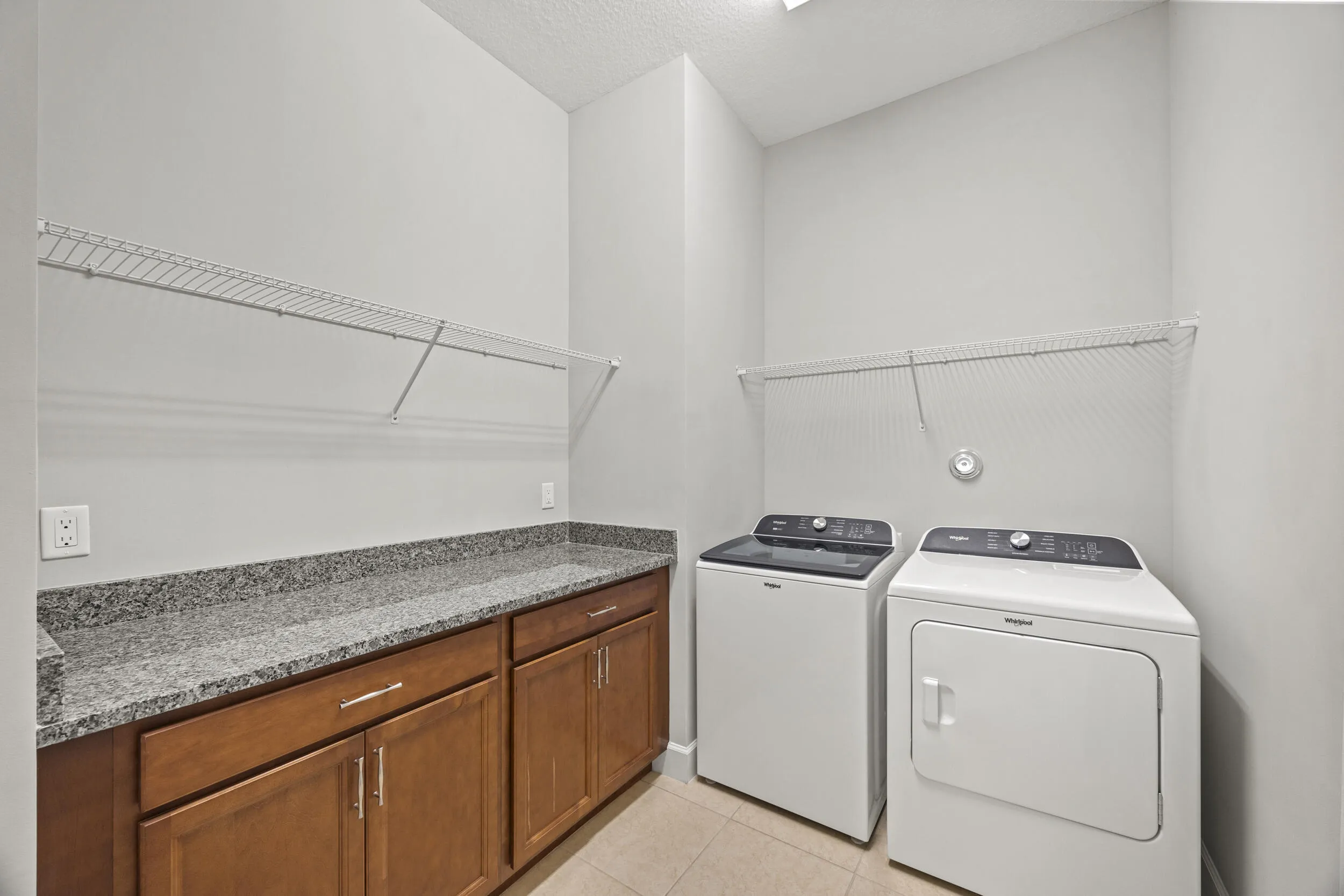 Laundry area featuring built-in cabinetry, granite-finish countertop, and wire shelving