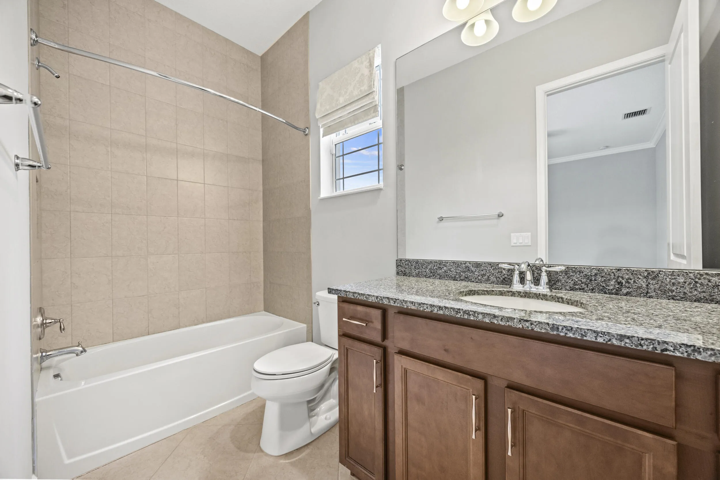 Bathroom featuring a wood-finish vanity with granite countertop, integrated sink, and chrome fixtures