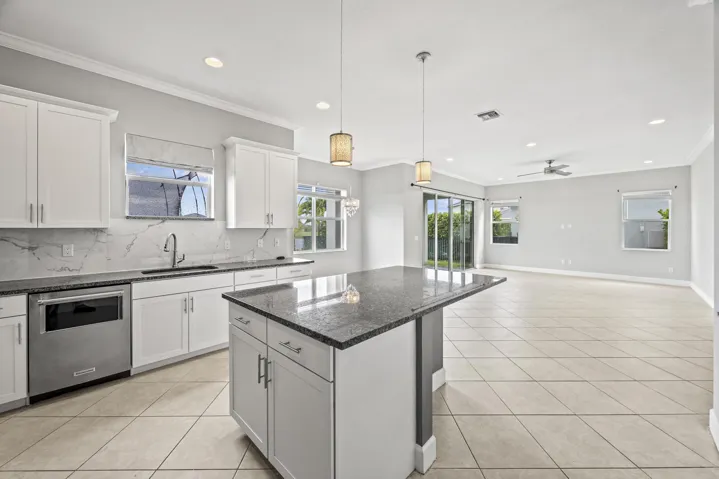 Spacious kitchen featuring white cabinetry, granite countertops, and a full-height backsplash