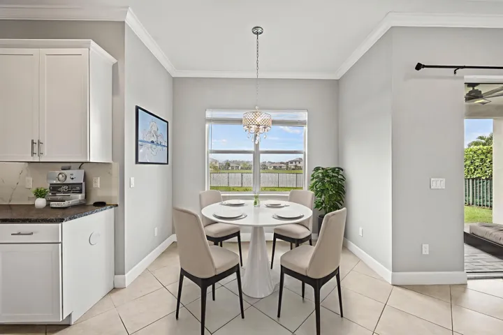 Kitchenette featuring white cabinetry, dark countertop, tile flooring, and a crystal chandelier