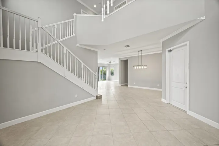 Foyer with tile flooring, white staircase with balusters, and a contemporary chandelier