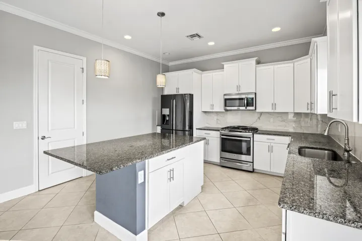 Kitchen featuring a central island with countertop, stainless steel appliances, white cabinetry, and tile flooring