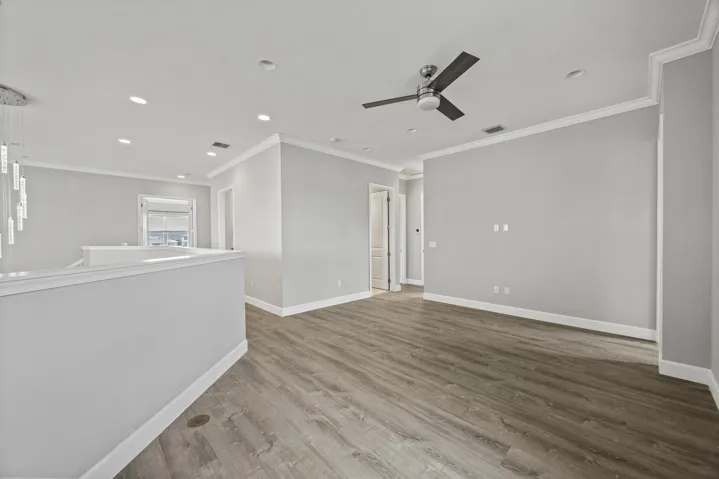 Wood-finish flooring, recessed lighting, ceiling fan, crown molding, and a contemporary chandelier