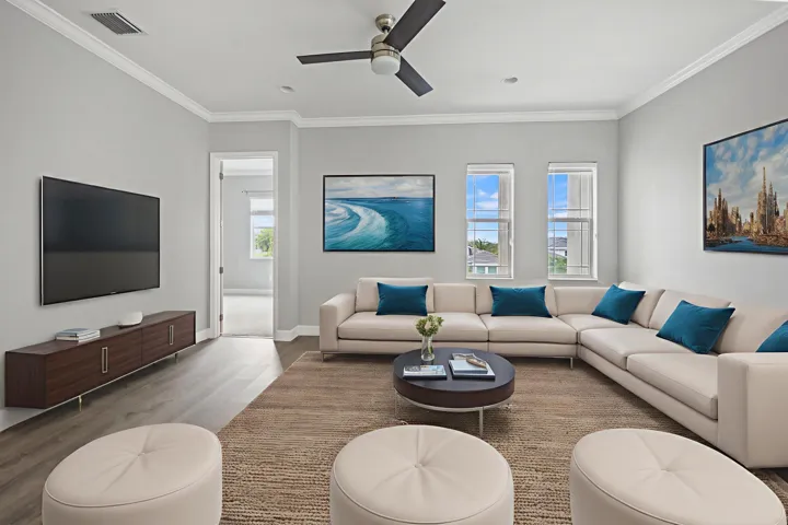 Spacious living area featuring wood-finish flooring, a ceiling fan, and crown molding