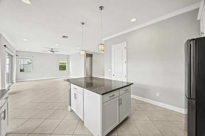 Open-concept living space featuring a kitchen island with stone countertop, tile flooring, and recessed lighting
