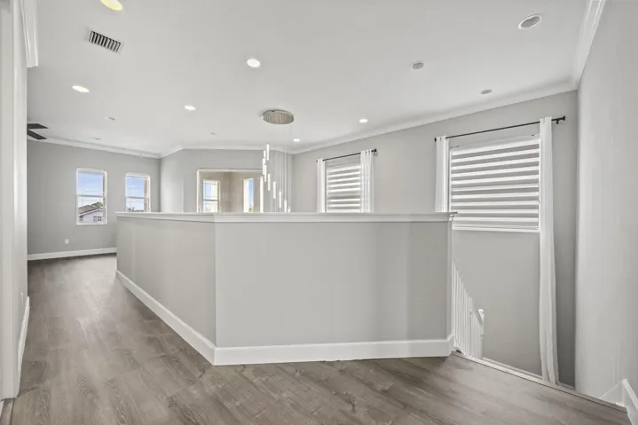 Wood-finish flooring, recessed lighting, crown molding, and multiple windows with blinds