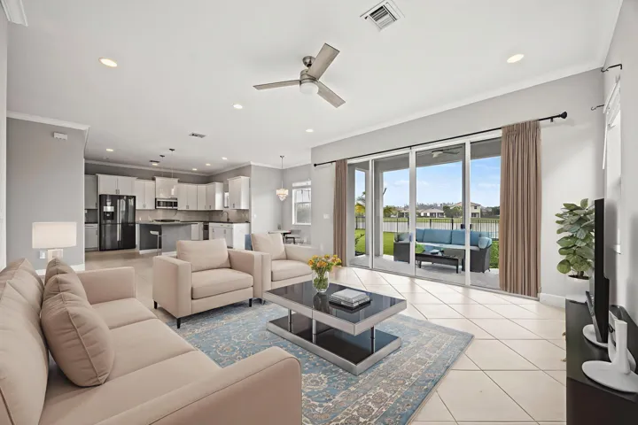 Spacious open-concept living area featuring large format tile flooring, crown molding, and recessed lighting