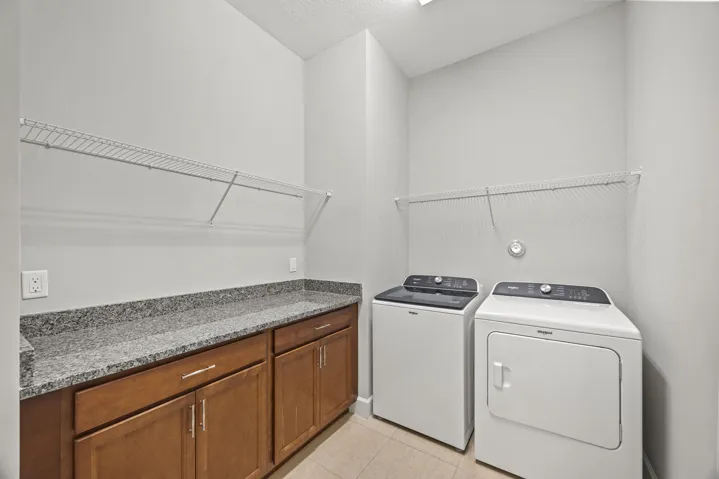 Laundry area featuring built-in cabinetry, granite-finish countertop, and wire shelving