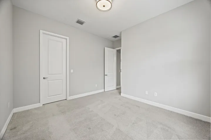Neutral-toned walls, plush carpeting, and a flush mount ceiling light fixture