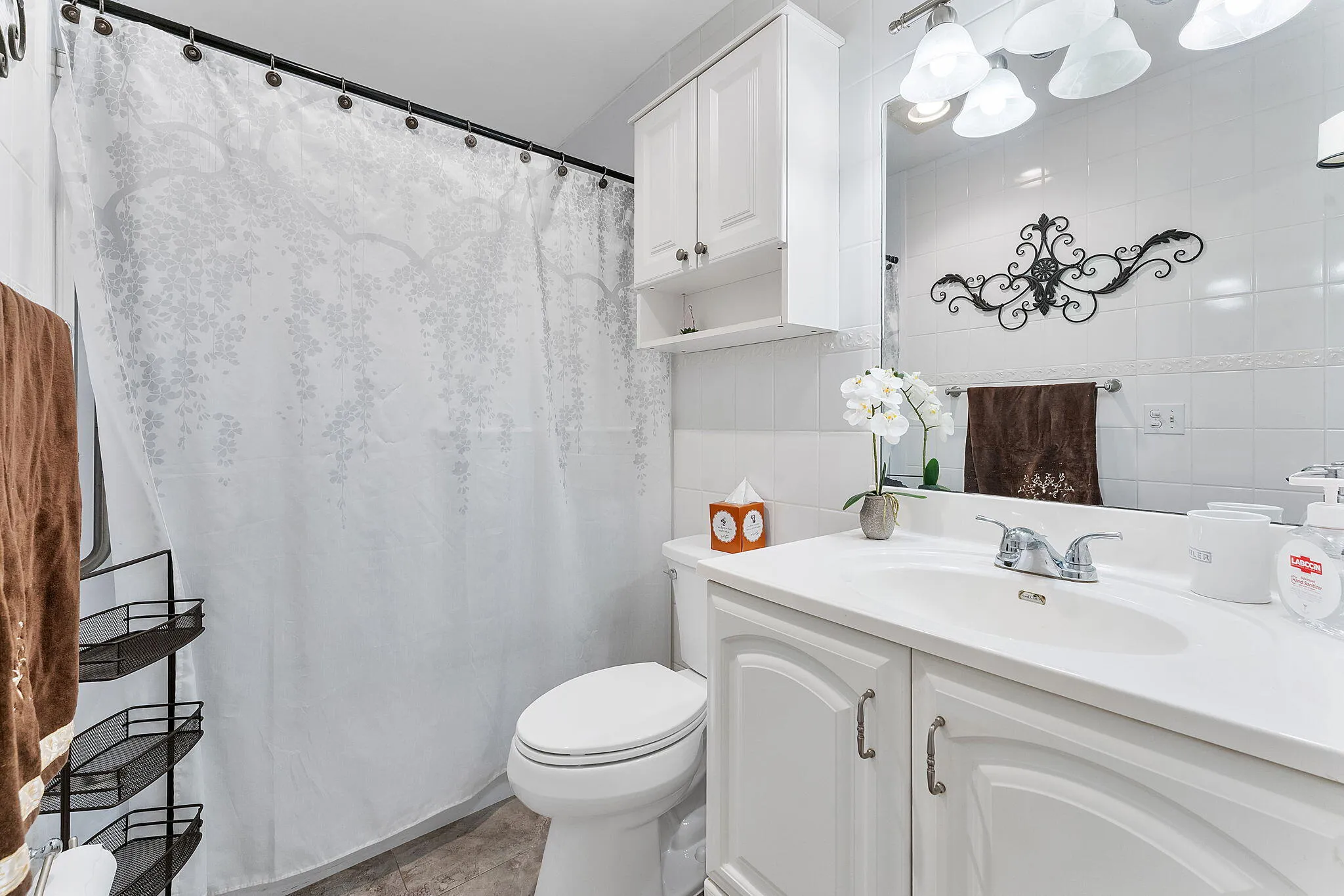 Contemporary bathroom featuring crisp white cabinetry with dual sink vanity, brushed nickel faucet fixtures, and white subway tile walls
