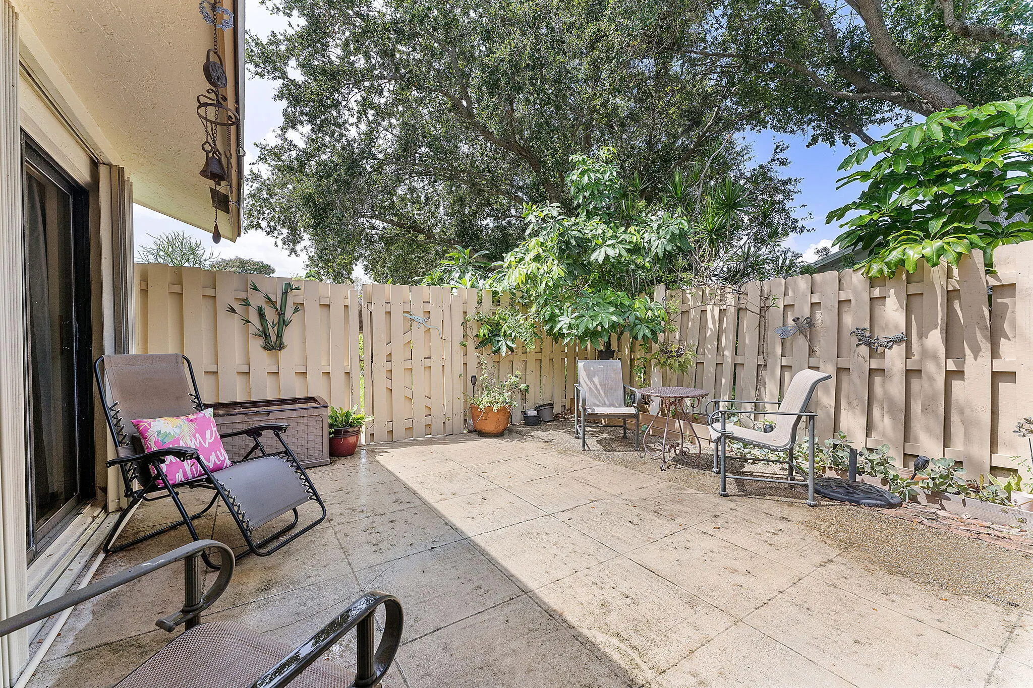 Private backyard retreat featuring mature shade trees, composite decking with integrated seating areas, wood-finish fencing, and direct access from the home