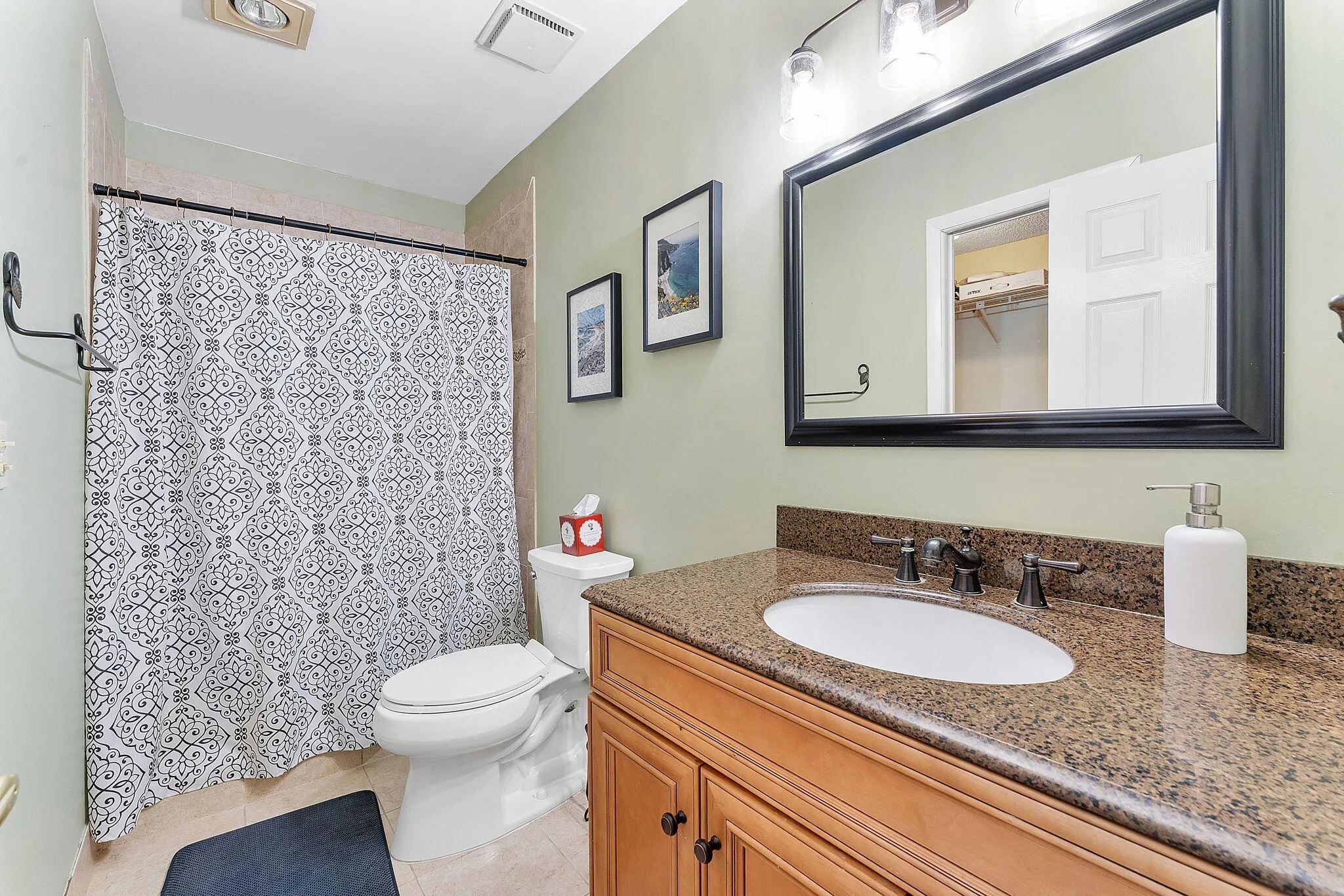 Spa-inspired bathroom featuring a dual-sink vanity with wood cabinetry, stone countertop, and brushed nickel fixtures