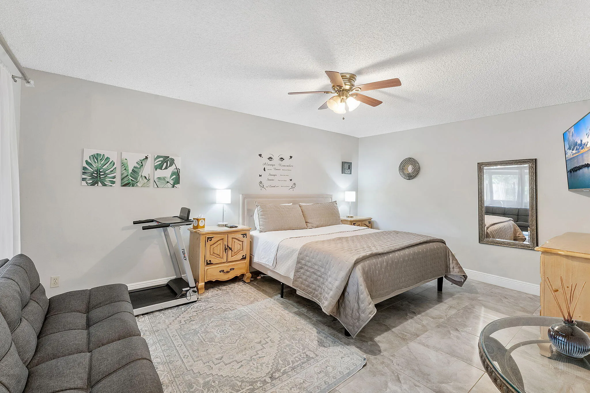 Spacious primary bedroom featuring neutral wall finishes, ceiling fan with integrated lighting, wood-finish nightstands, and neutral-toned bedding