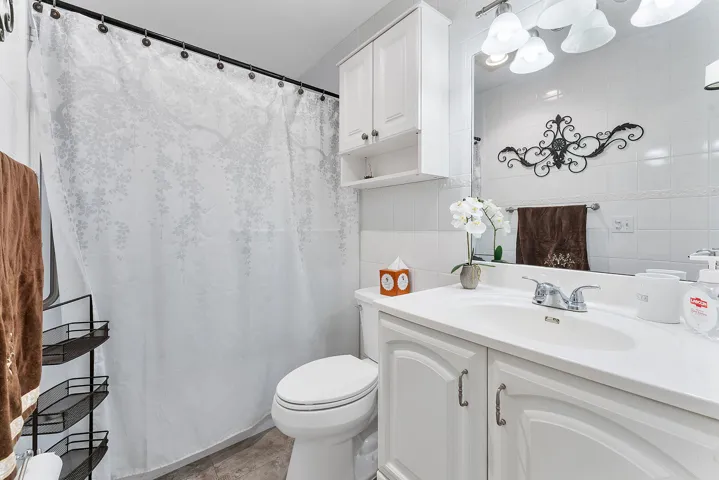 Contemporary bathroom featuring crisp white cabinetry with dual sink vanity, brushed nickel faucet fixtures, and white subway tile walls