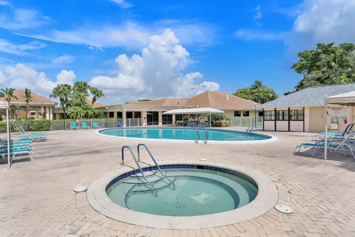 Resort-style community amenities featuring a sparkling lagoon-form swimming pool with designated shallow-water lounging area, circular spa, and expansive paver decking