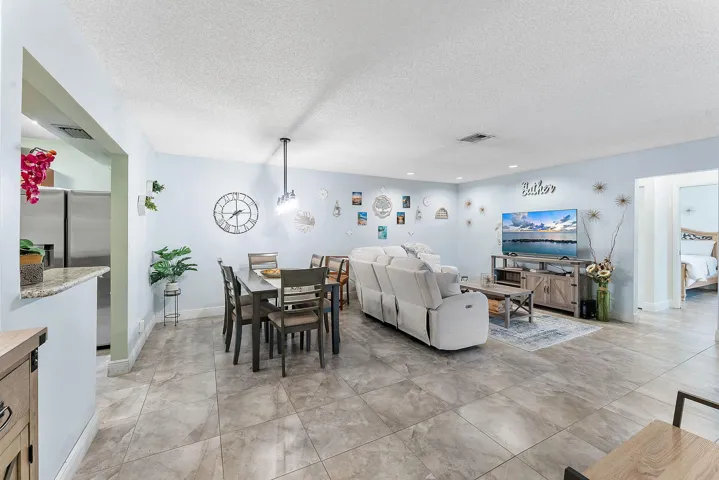Open-concept living area showcasing polished stone-finish flooring, recessed lighting, and abundant natural light from multiple windows