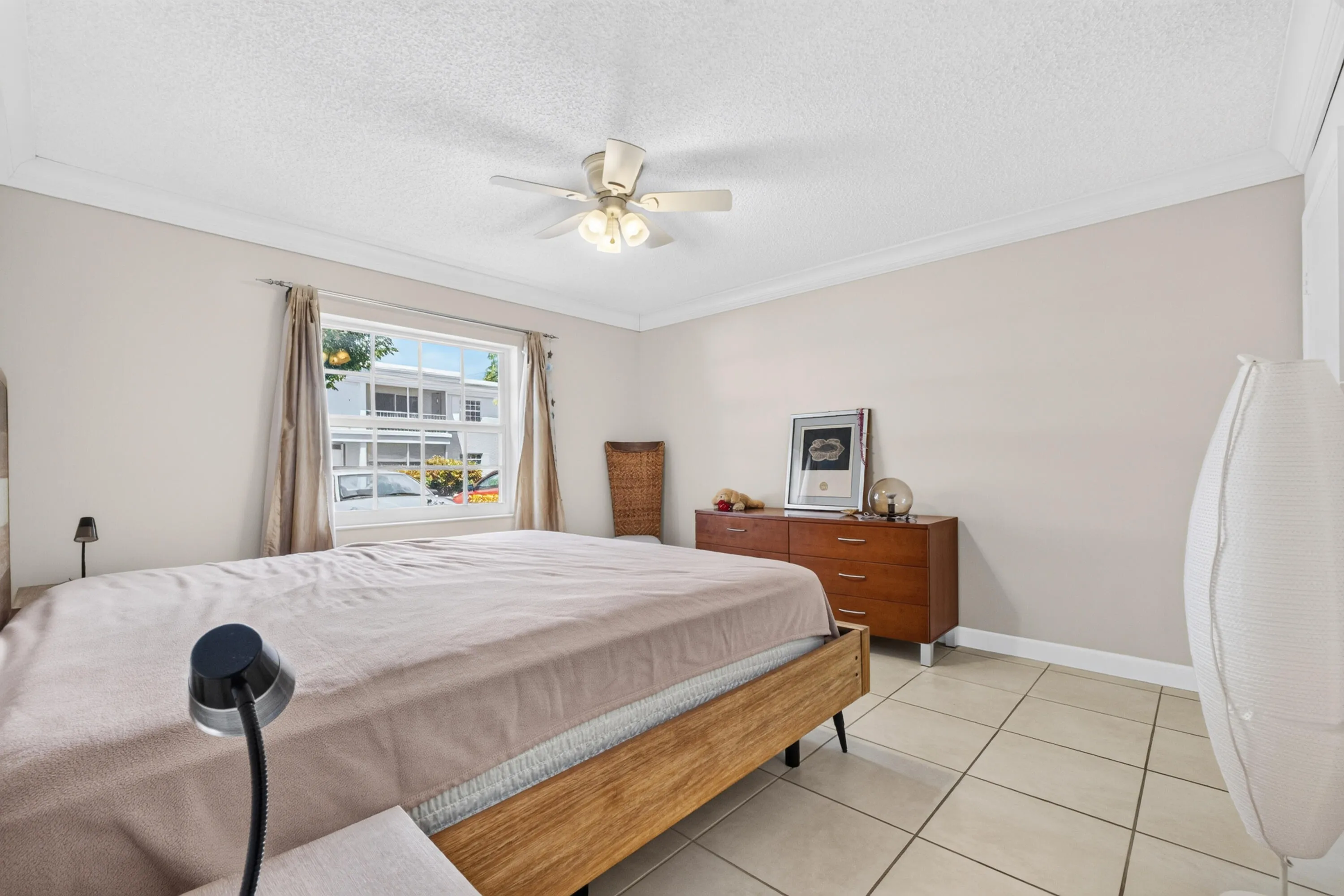 Recessed window with white trim, ceiling fan, crown molding, and tiled flooring