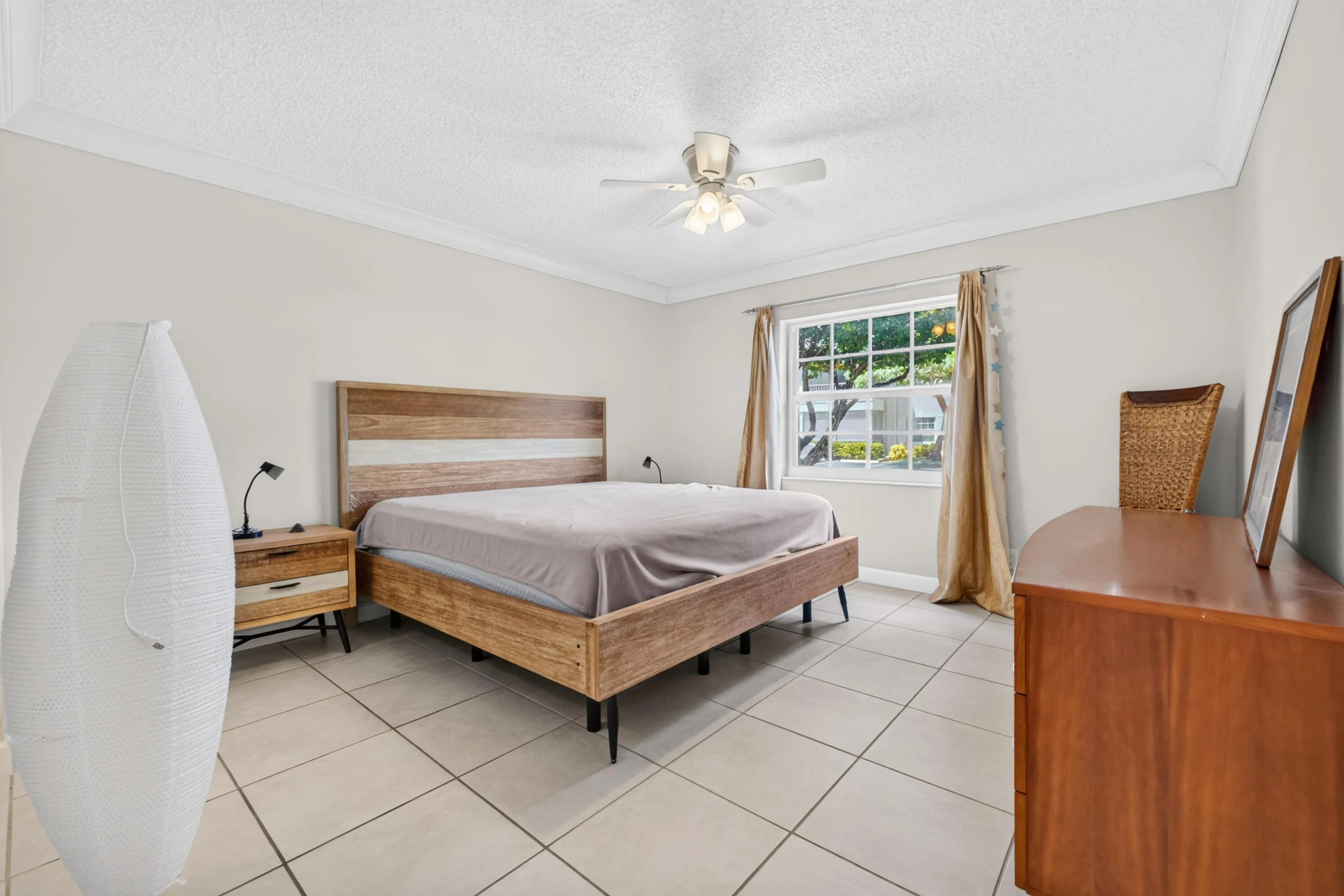Crown molding, tiled flooring, ceiling fan, and window with outdoor greenery