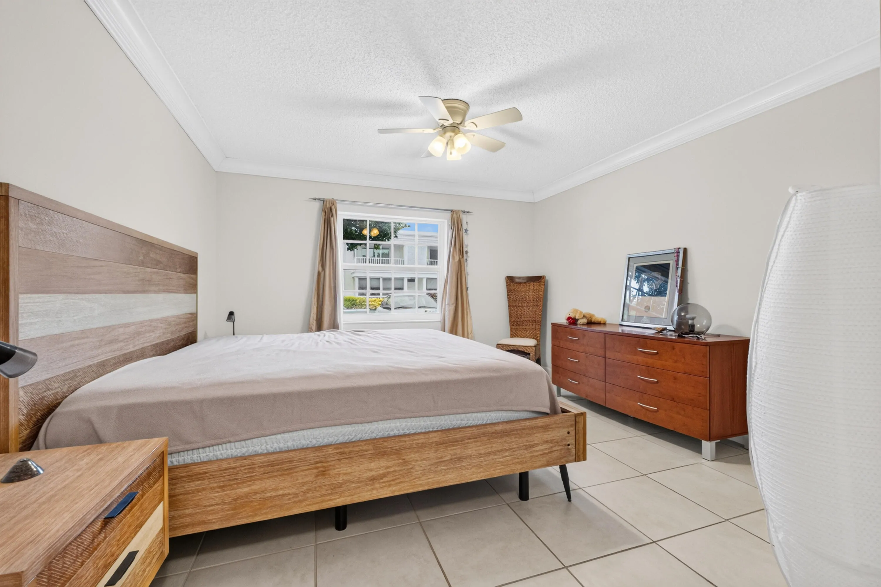 Crown molding, ceiling fan, window with horizontal muntins, and tiled flooring