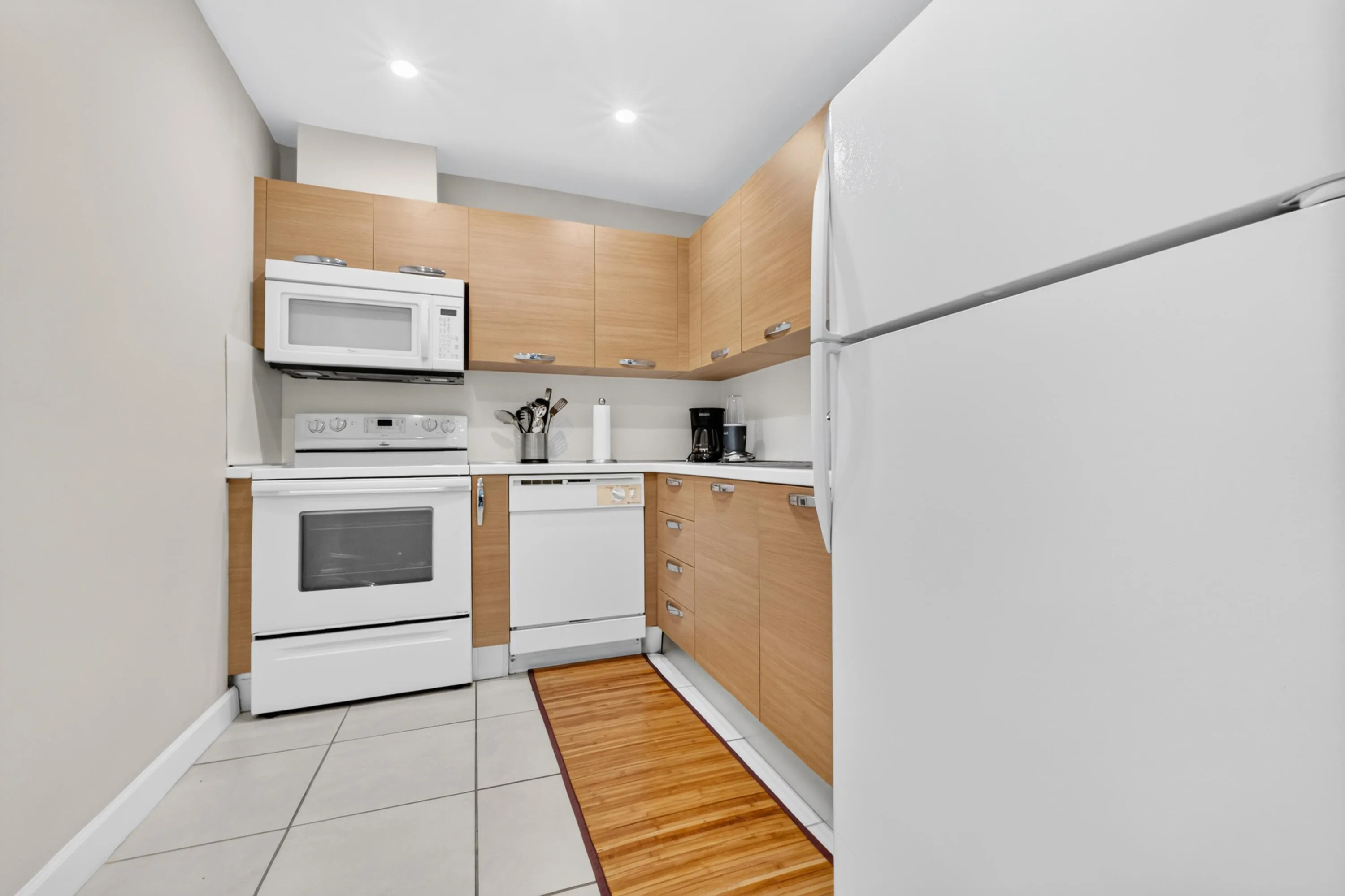 Kitchen featuring wood-finish cabinetry, white appliances, built-in microwave, white countertops, and recessed lighting