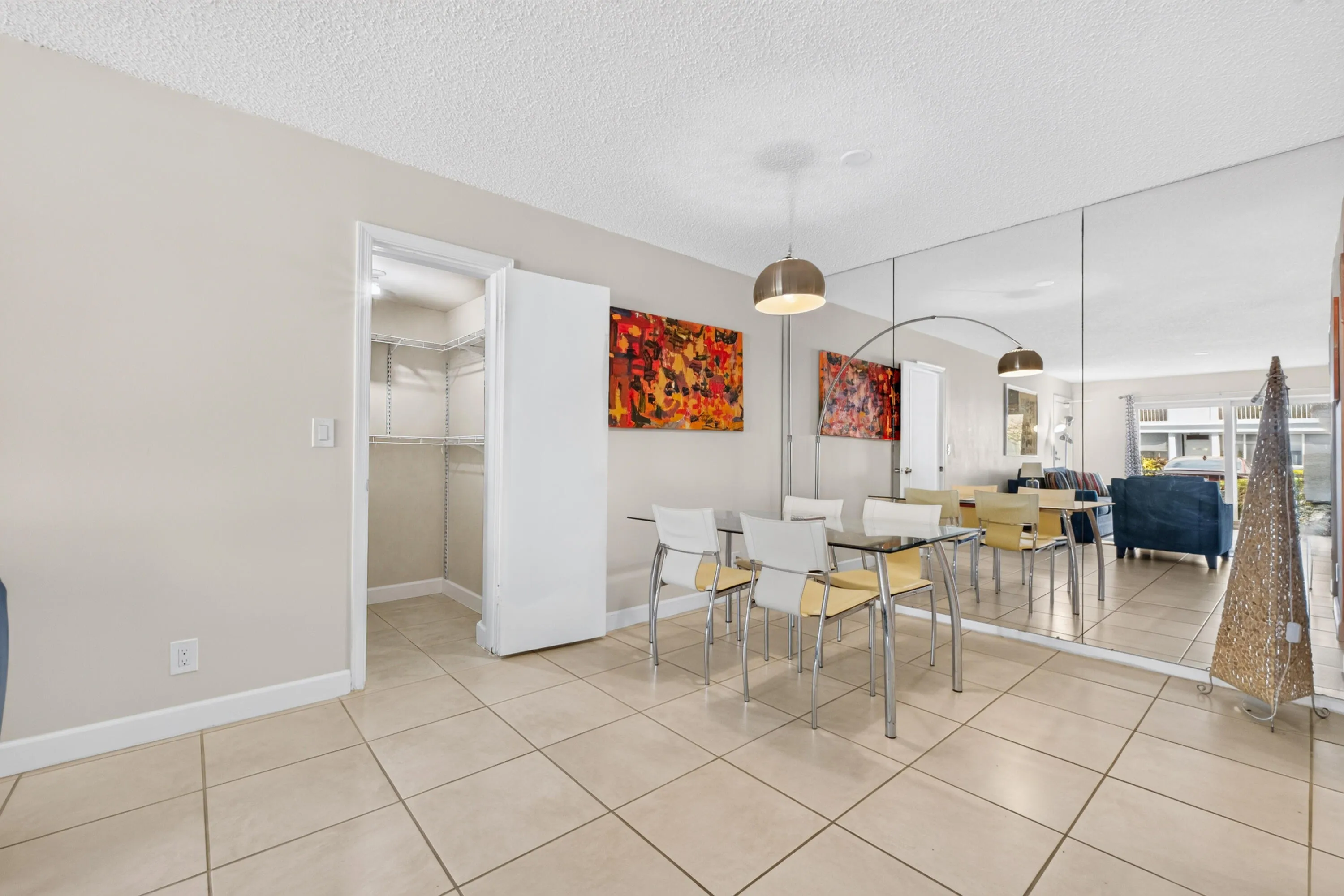 Tile flooring throughout, full-wall mirror, pendant lighting, and a built-in closet system