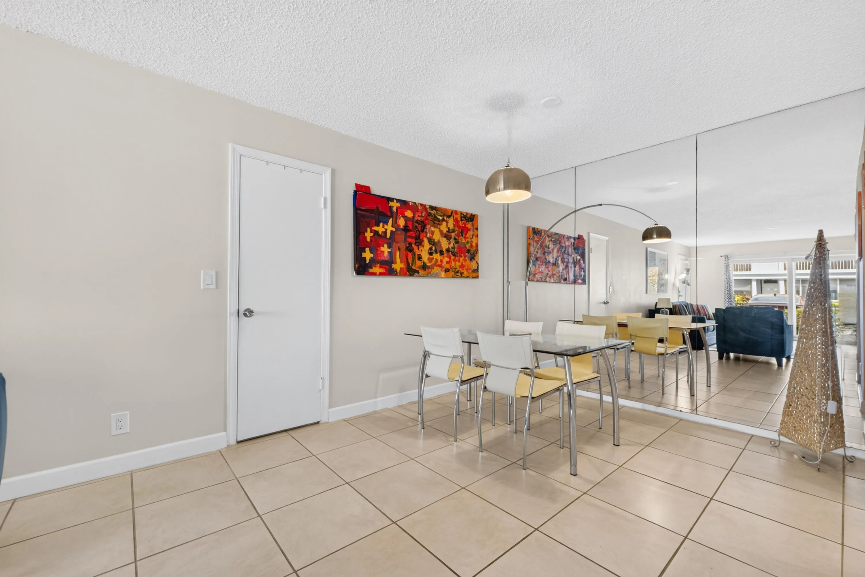 Open dining area with neutral tile flooring, contemporary pendant lighting, and large mirror wall accents
