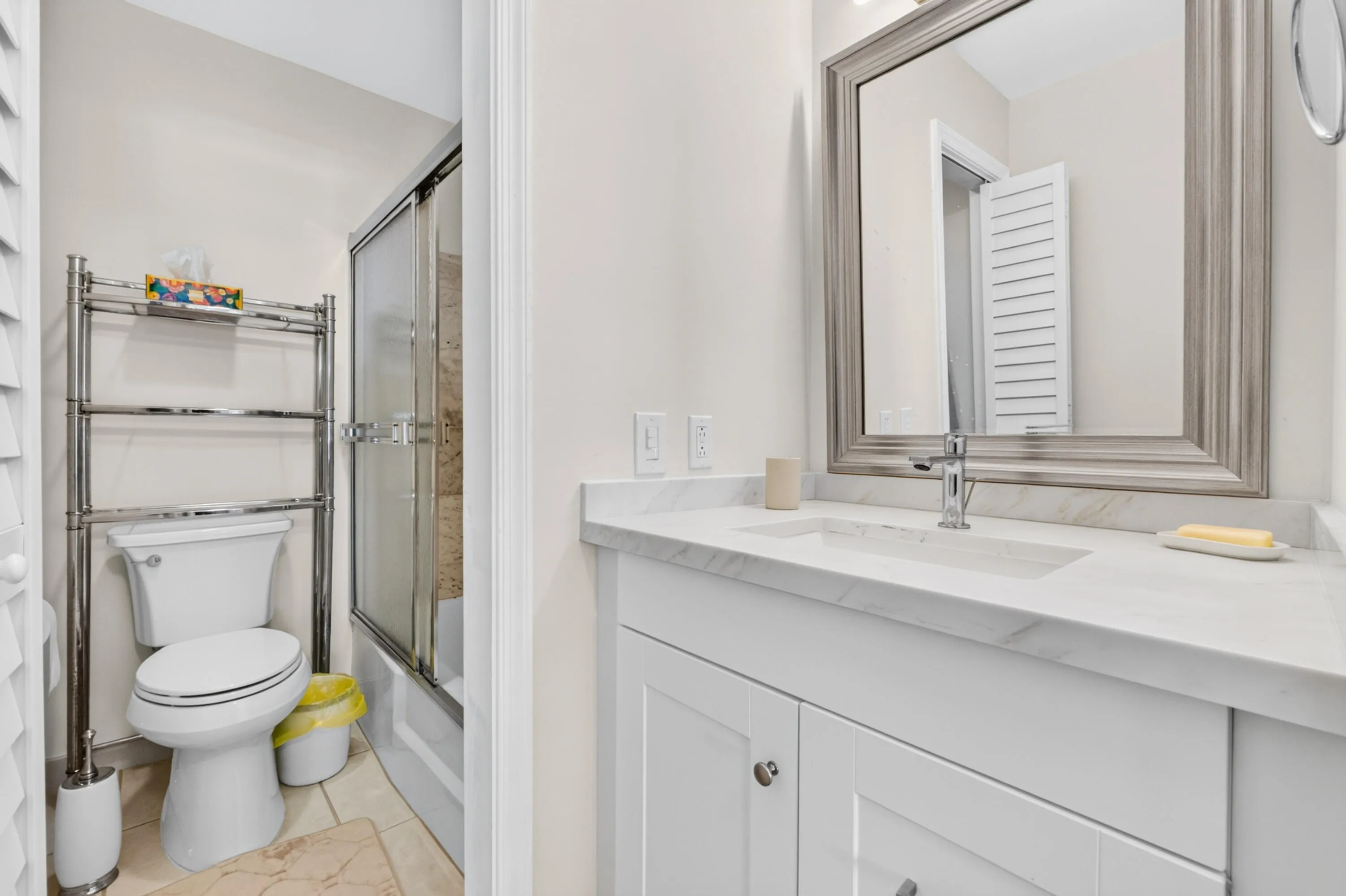 White vanity with a light-colored countertop, framed mirror, and a chrome faucet