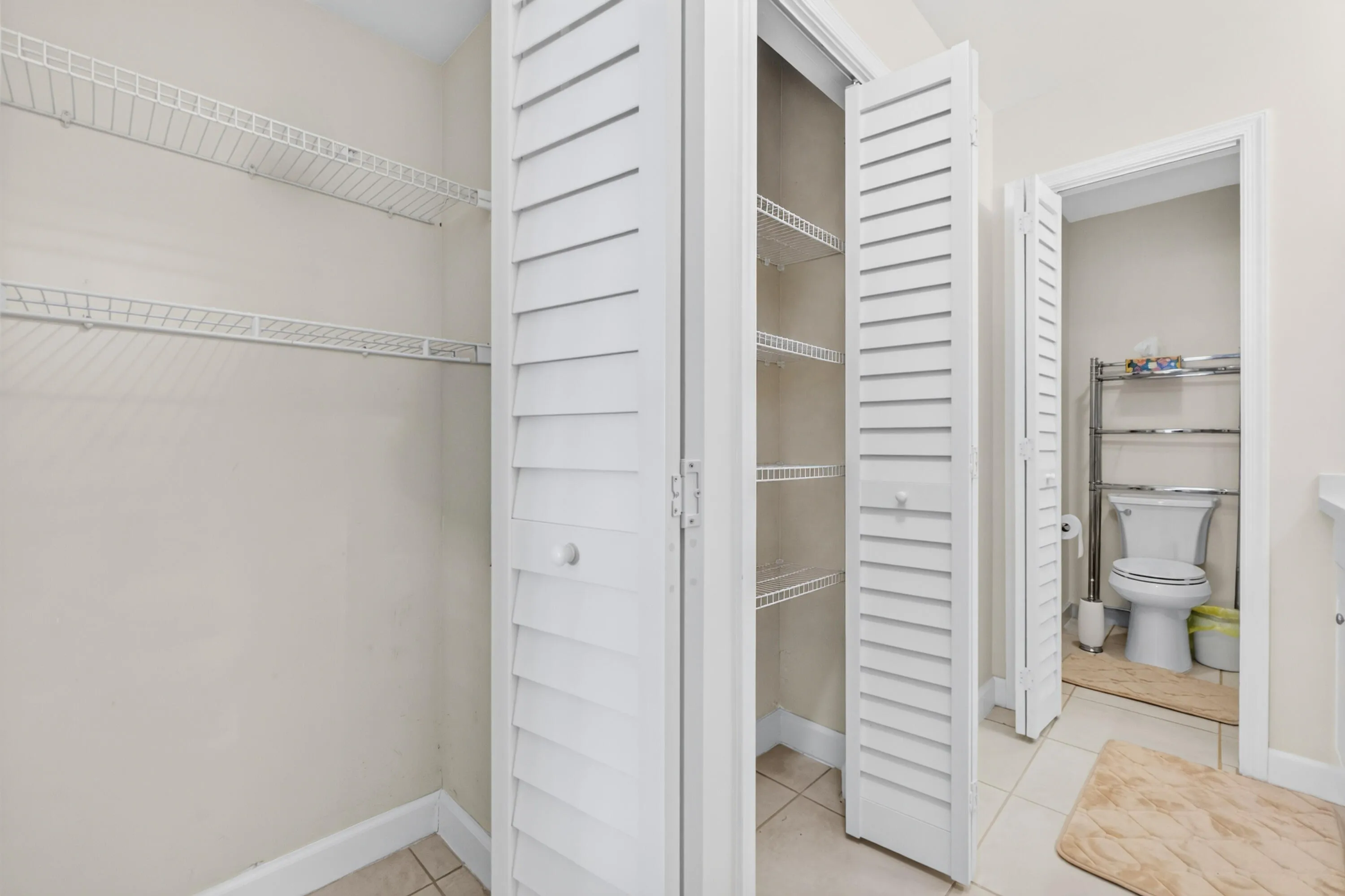 Spacious walk-in closet with louvered double doors, multiple shelving units, and abundant storage capacity