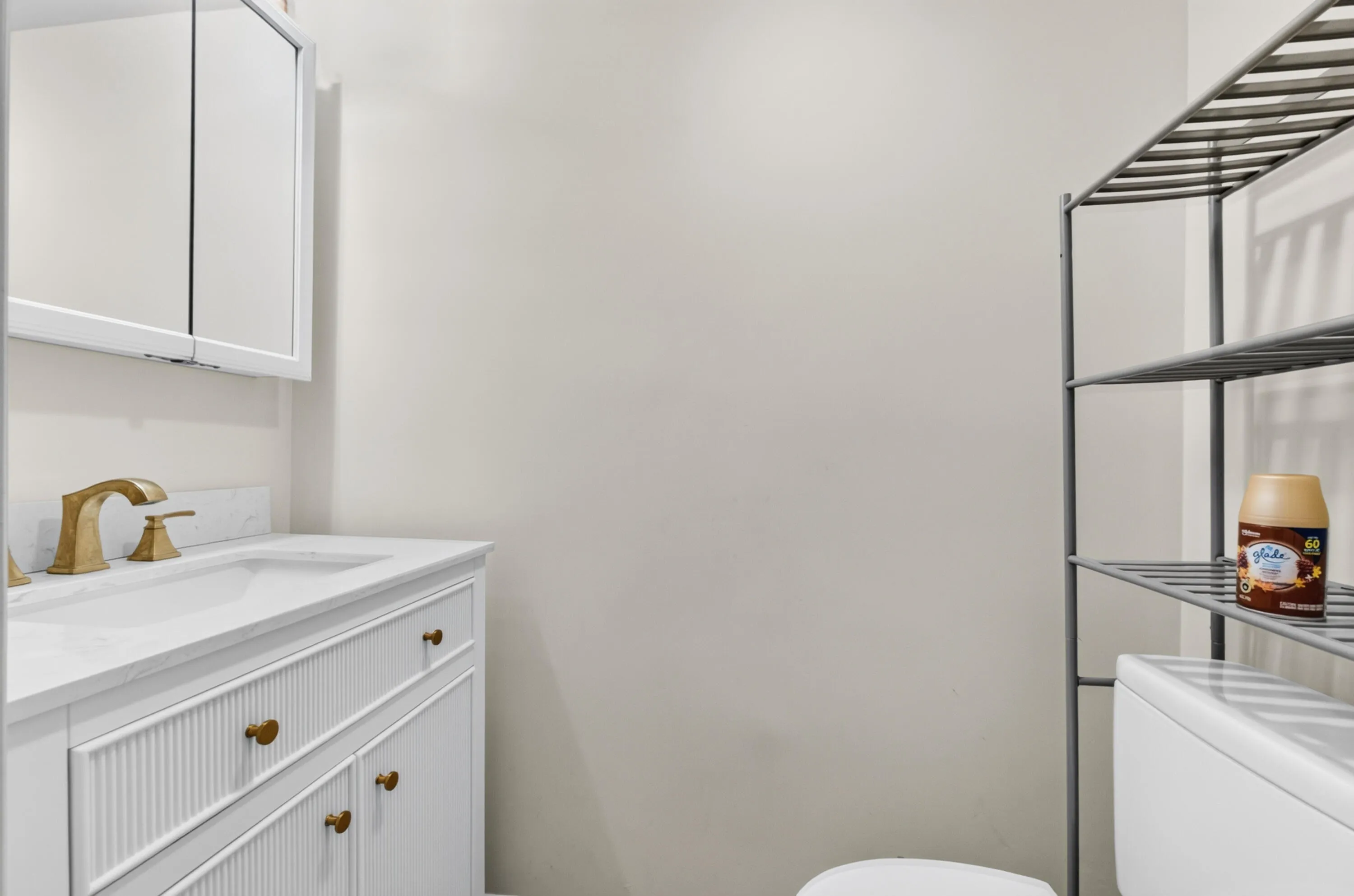 Spa-inspired bathroom featuring a white vanity with ribbed cabinetry, white quartz countertop, and brass-finish faucet