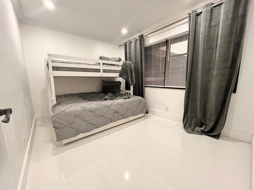 Recessed lighting illuminates a room featuring white walls and white tiled flooring